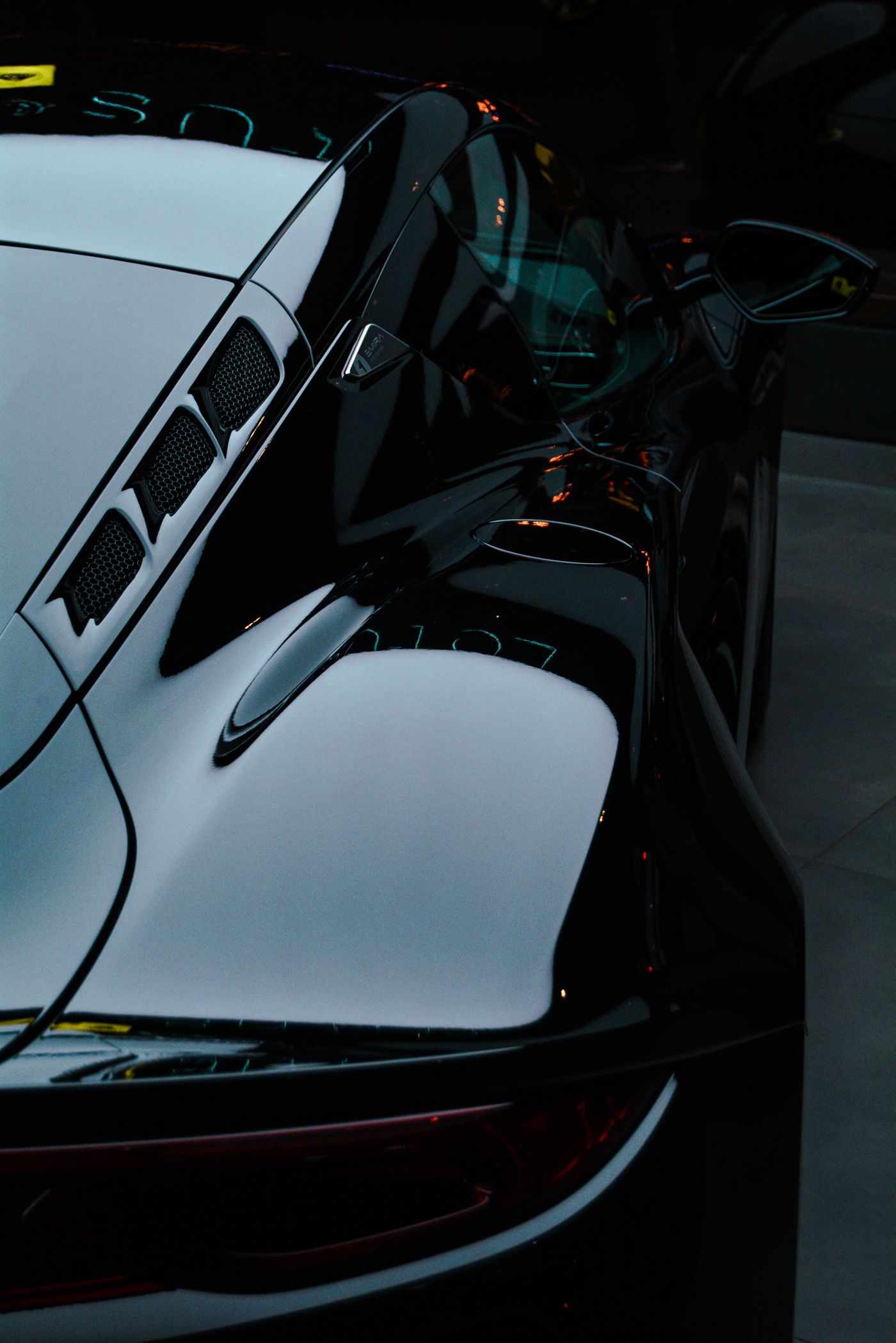 Glossy black sports car bodywork reflecting studio lights