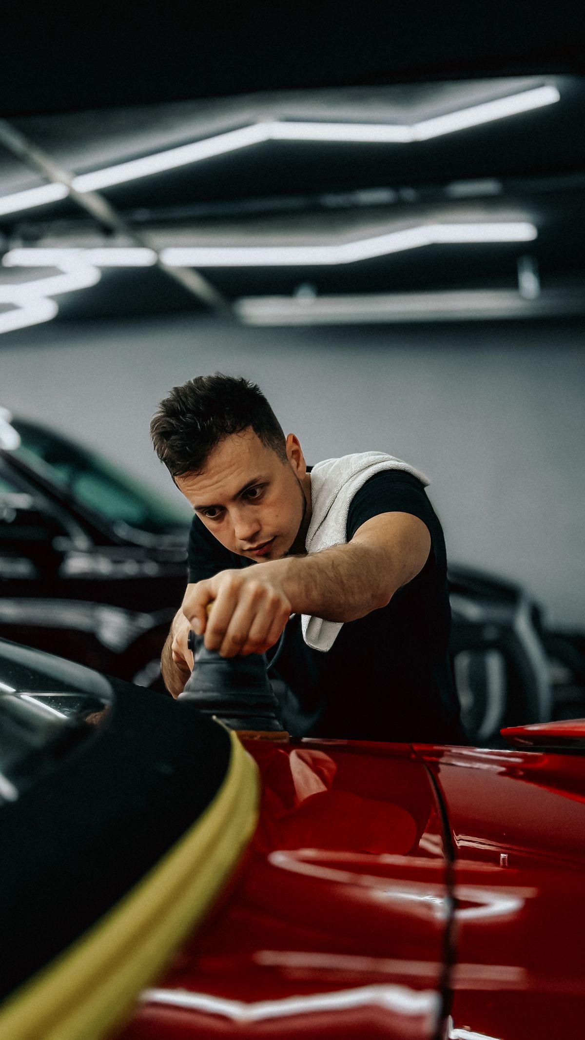 Detailer running a polisher across the paint of a red car