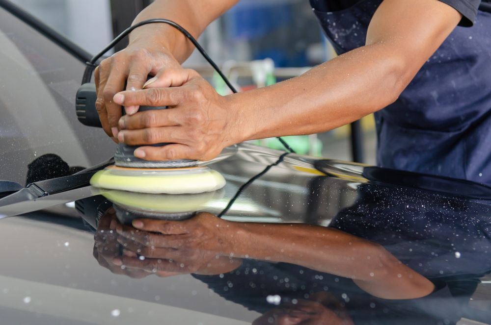 Polisher working a black hood to a mirror shine
