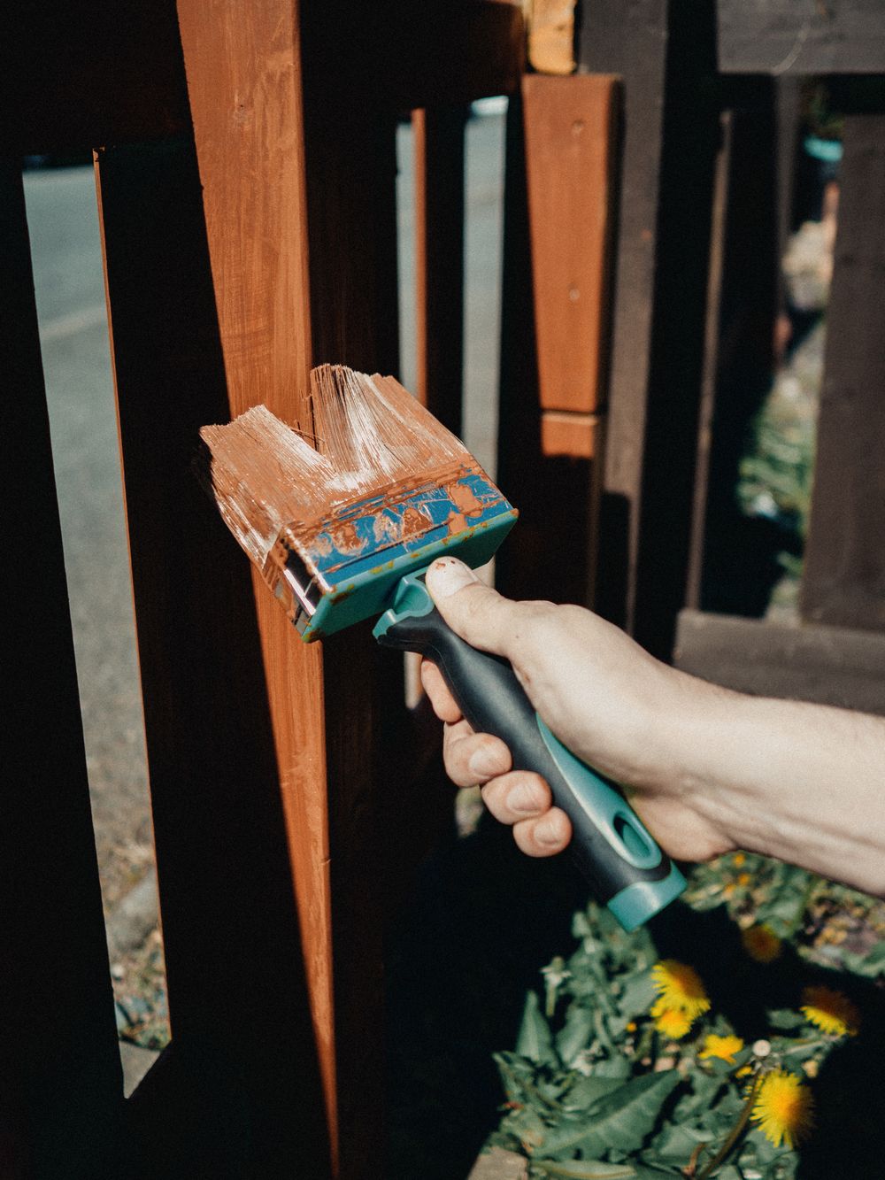 Brush applying stain to dark wood slats