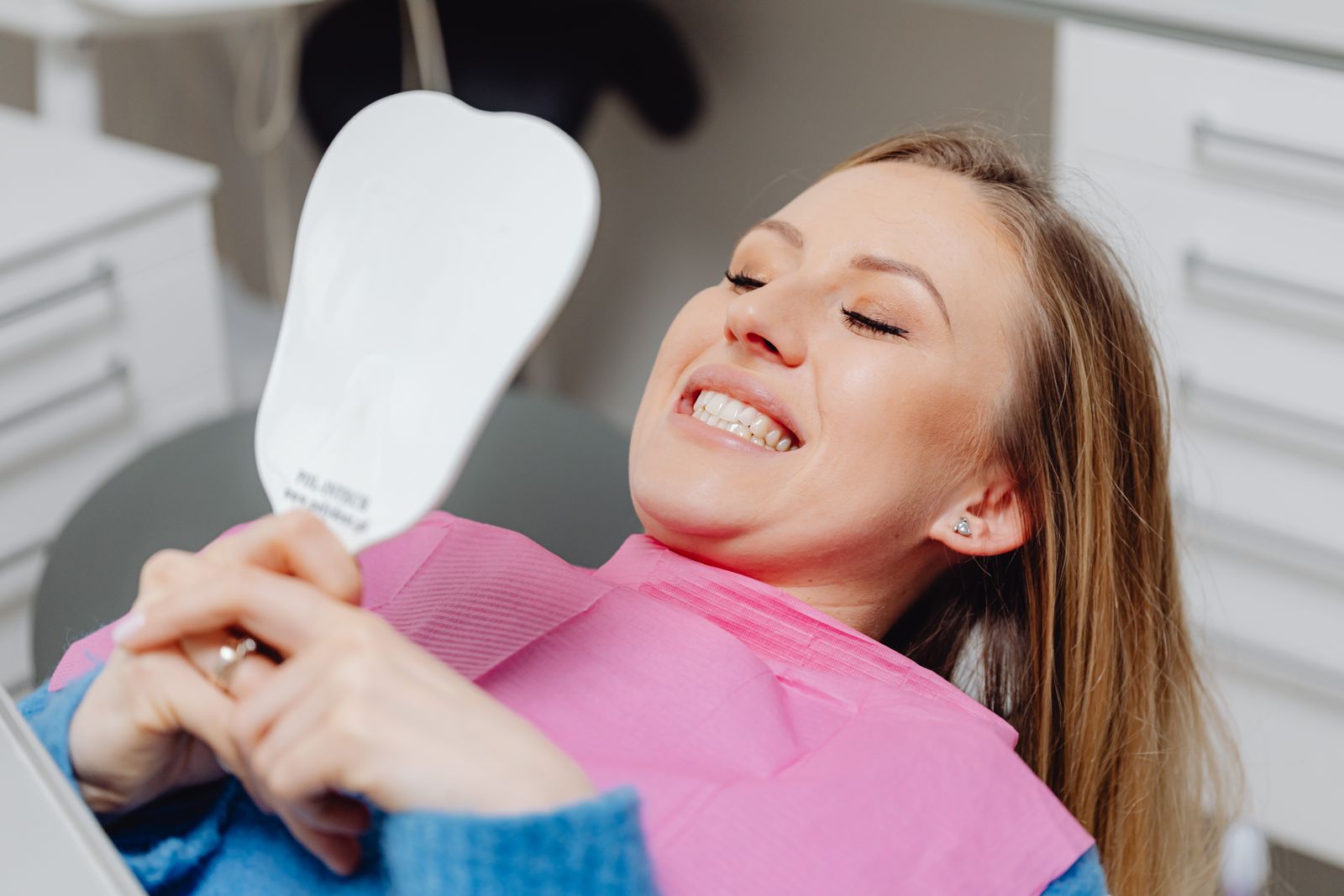 Smiling patient checking her new smile in a mirror