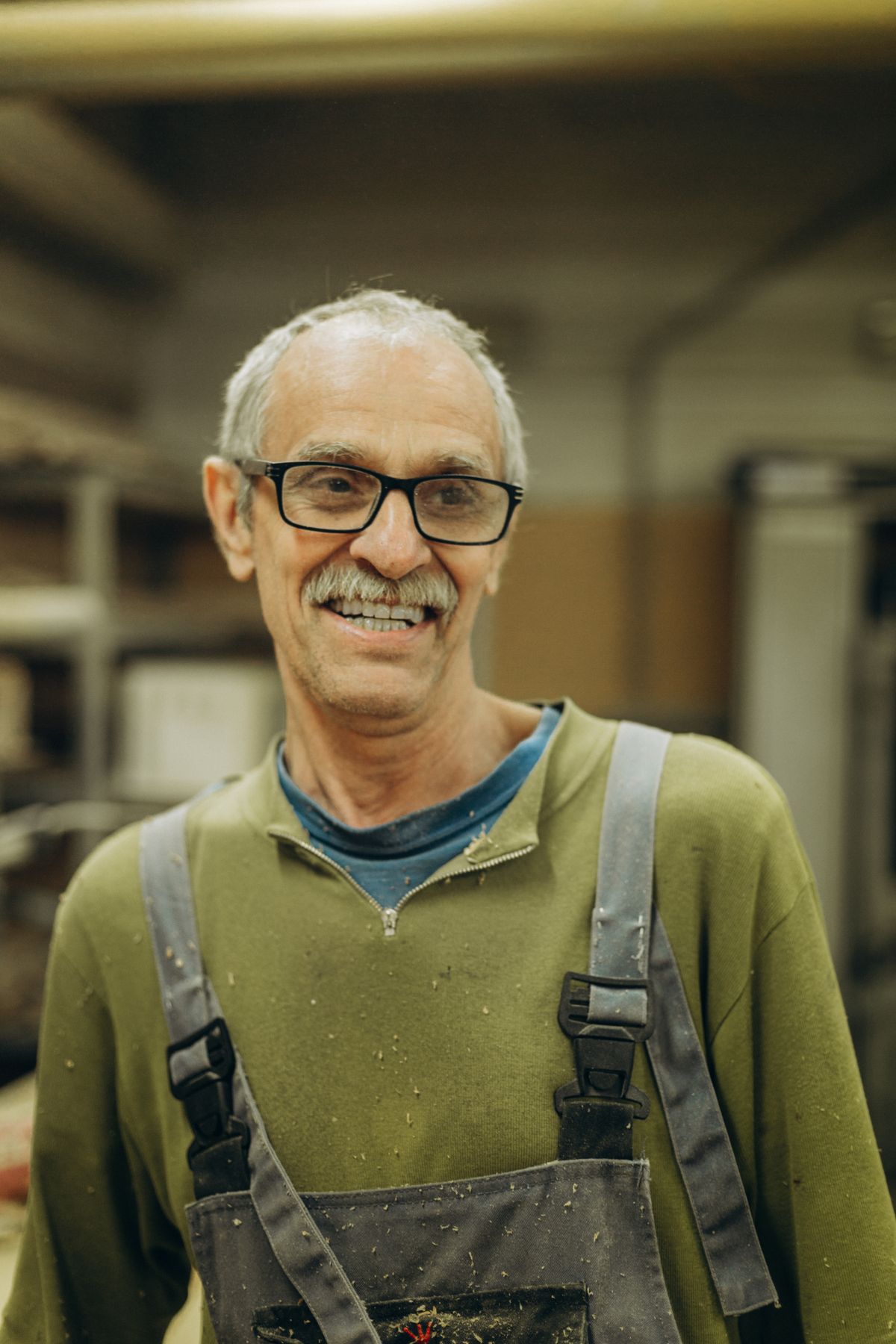 Smiling tradesman in work overalls in his workshop