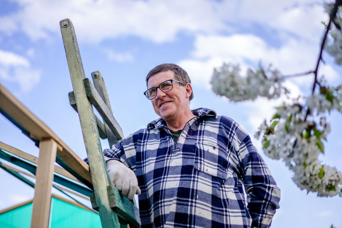 Smiling Overflow founder in a flannel shirt leaning on a wooden ladder