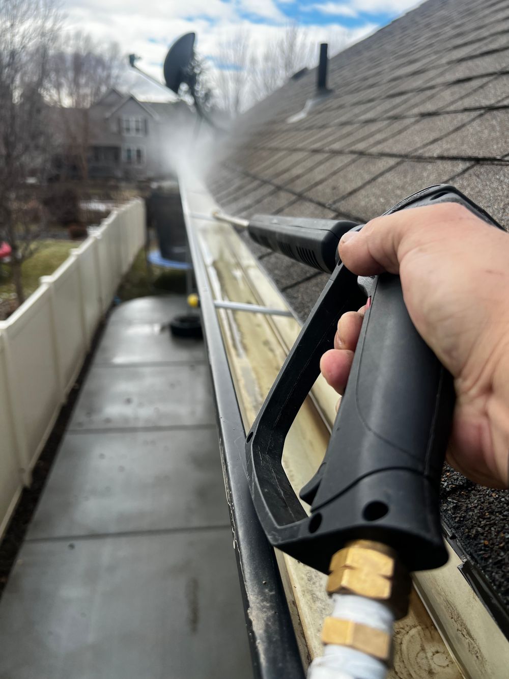 Water wand flushing debris out of a roof gutter