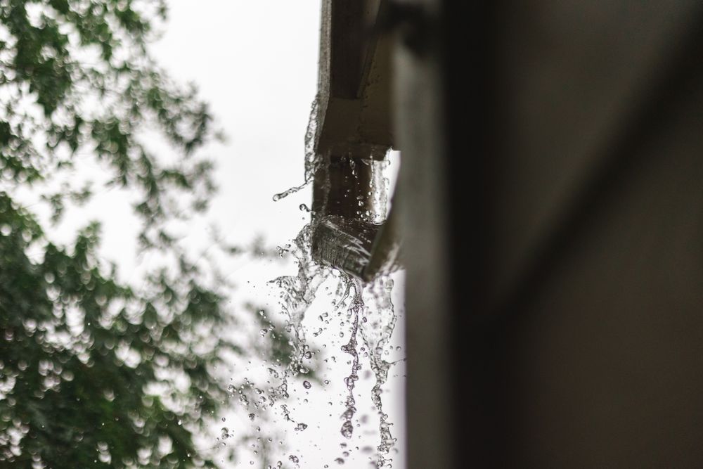 Rainwater spilling from a roof gutter during a downpour