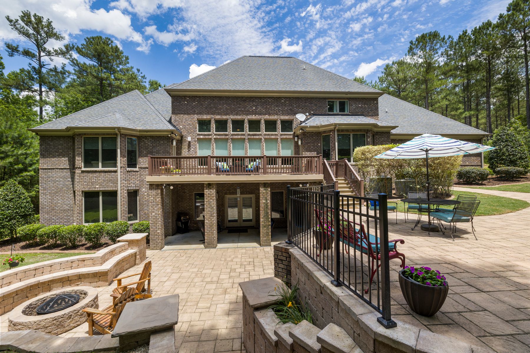 Paver patio with a fire pit and stone seat walls behind a brick home