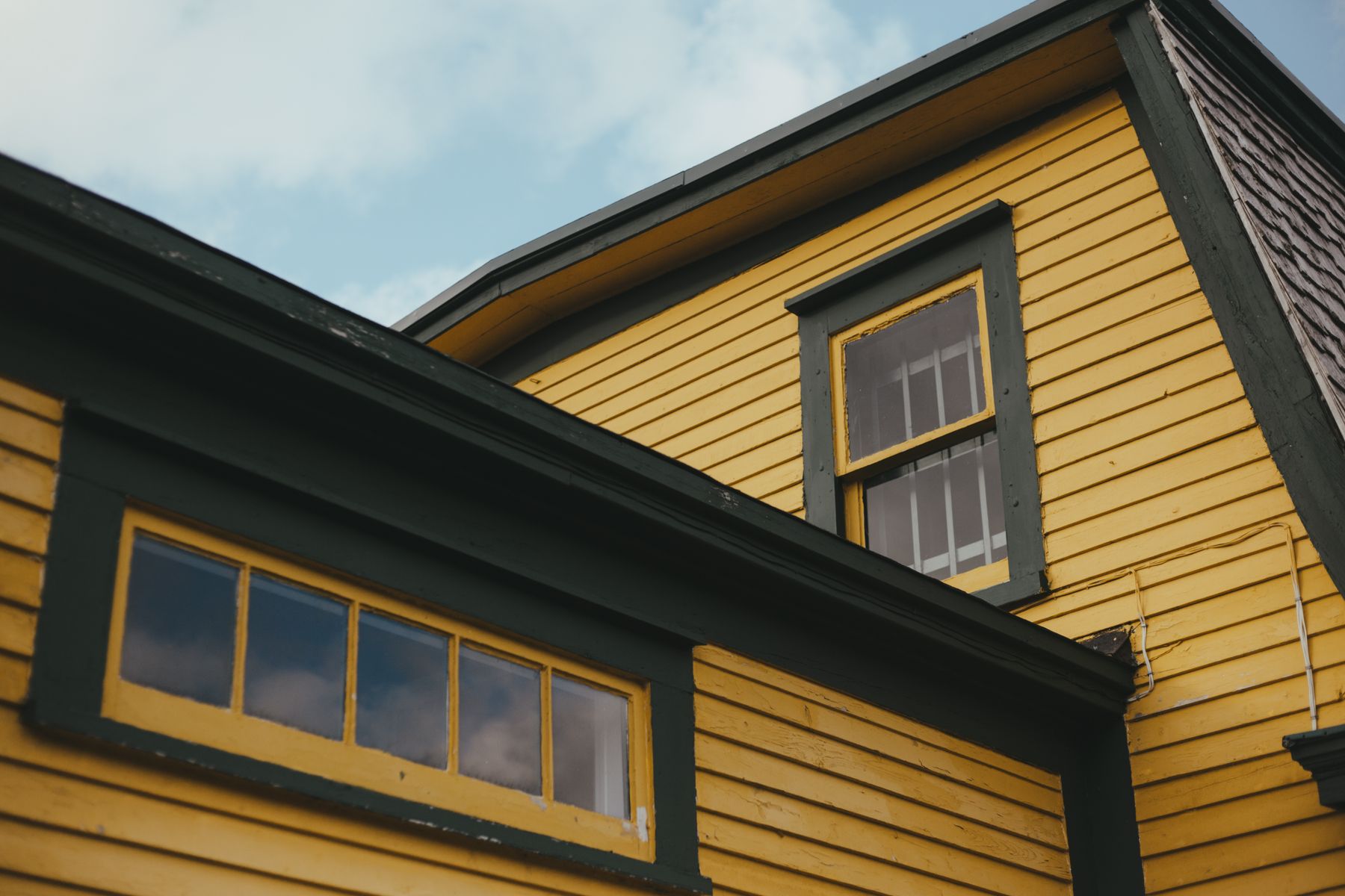 Yellow siding with dark green window trim