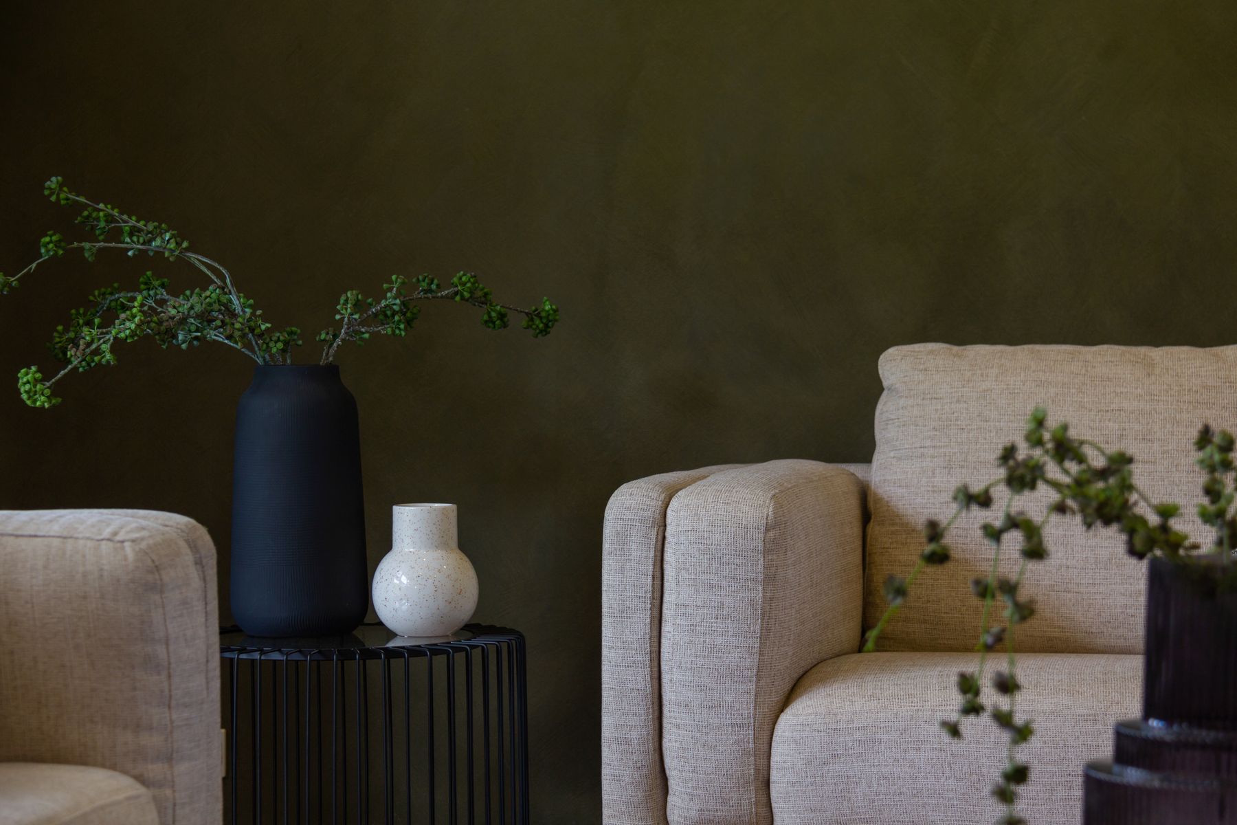 Living room with a deep olive painted wall and cream armchairs