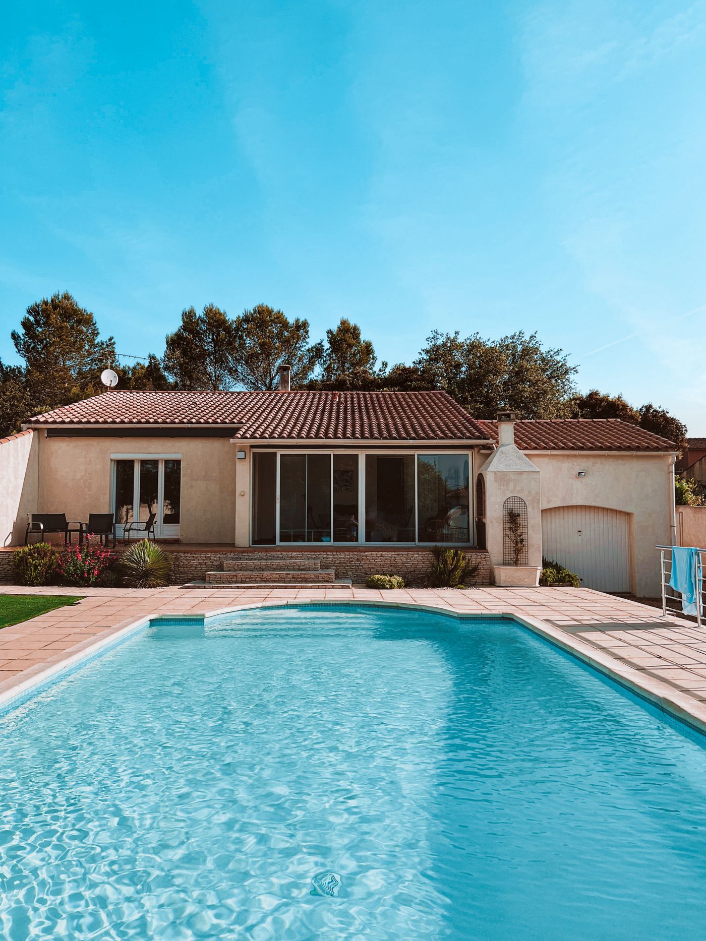 Rectangular pool with a paver deck in front of a single-story house