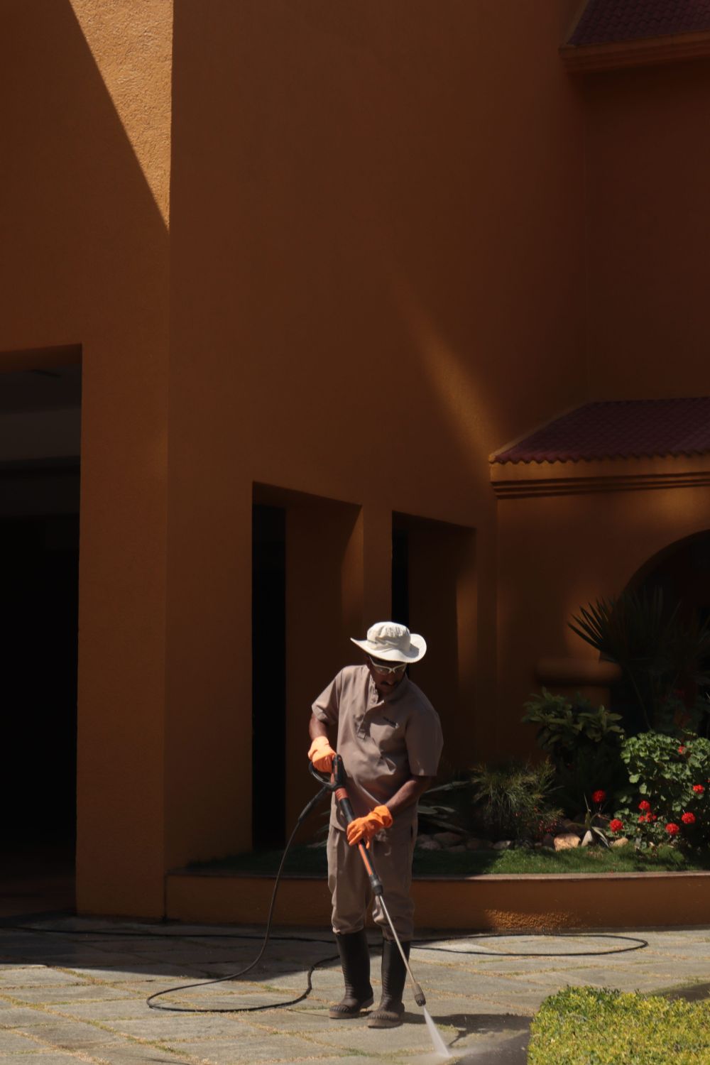 Worker pressure washing a walkway outside a stucco building